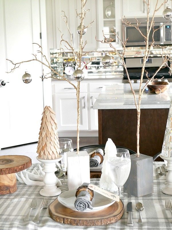 Cozy and Elegant Winter Table Setting with rustic trees and wood rounds