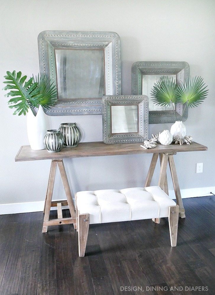 Rustic Chic Entry Way with sawhorse console table and oversized rustic mirror with pops of tropical leaves! Love this look for a classy summer!