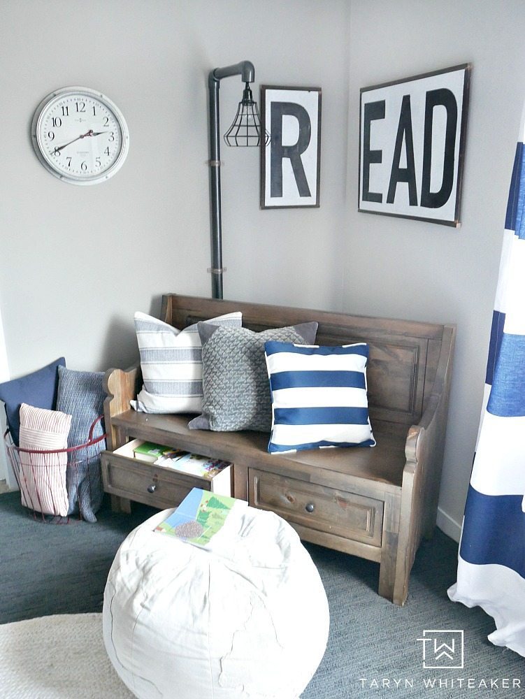 An adorable reading nook for a little boys room! Such a cute wooden farmhouse sign with a church pew bench and industrial light!