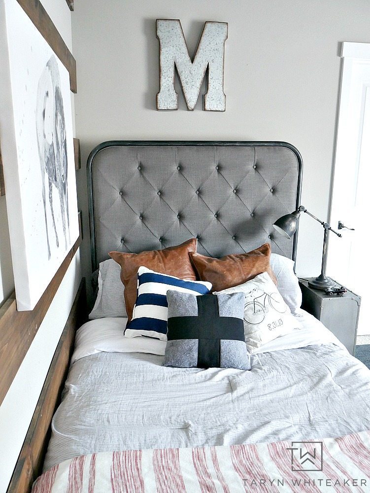 Adorable modern farmhouse bedding for a boy room! Love this oversized gray tufted headboard with leather pillows and lots of texture. 