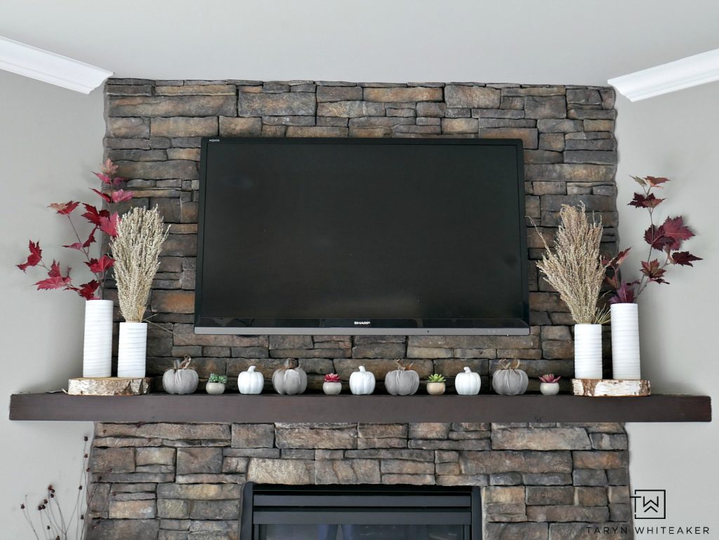 Create a modern boho fall mantel display using a mixture of deep reds, neutrals tones and lots of texture. This is a great look for fall with the earth tones against the stone fireplace. 