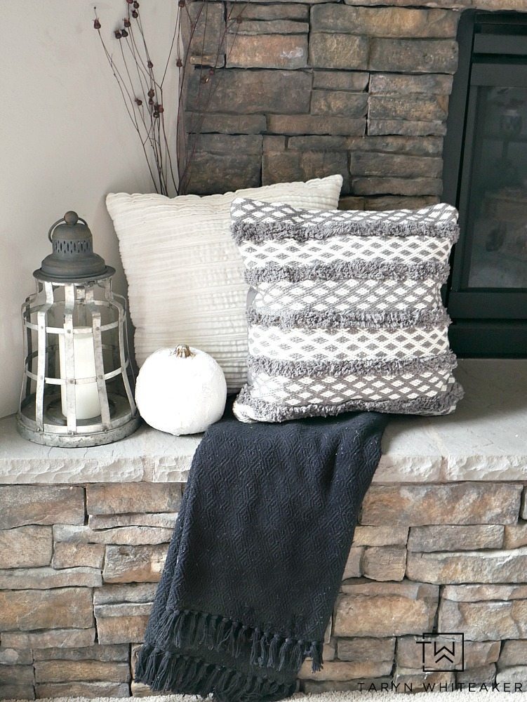 Create a modern boho fall mantel display using a mixture of deep reds, neutrals tones and lots of texture. This is a great look for fall with the earth tones against the stone fireplace. 