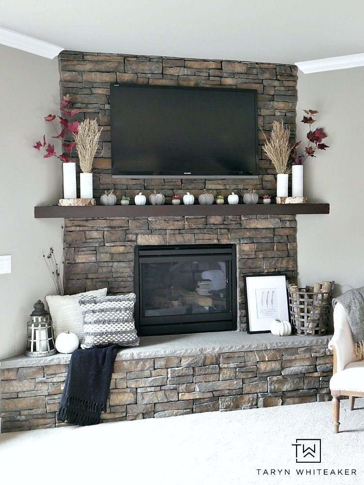 Create a modern boho fall mantel display using a mixture of deep reds, neutrals tones and lots of texture. This is a great look for fall with the earth tones against the stone fireplace. 