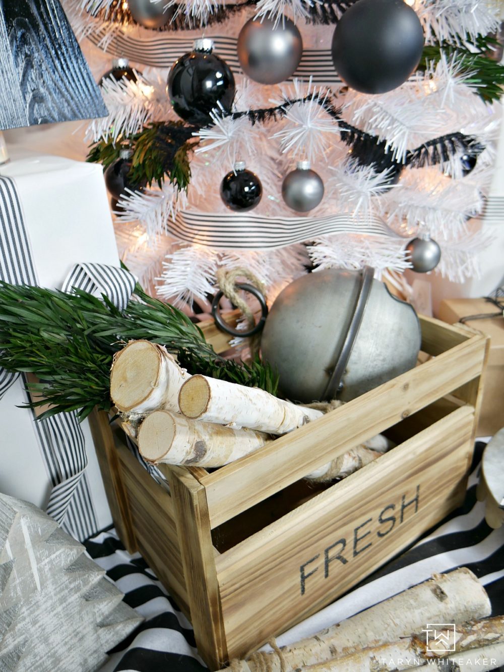Taryn creates this Modern Black and White Christmas Tree display in her home using a tall white skinny tree with black and silver ornaments and wood!