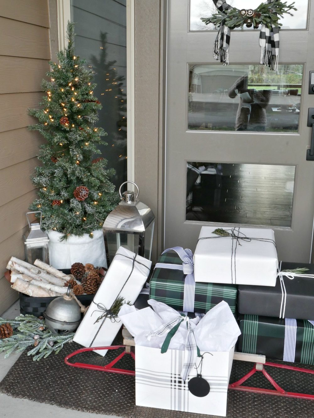 Green and Black Christmas Porch featuring mini trees, a sweater wreath and lots of wintery accents for a festive yet elegant look!