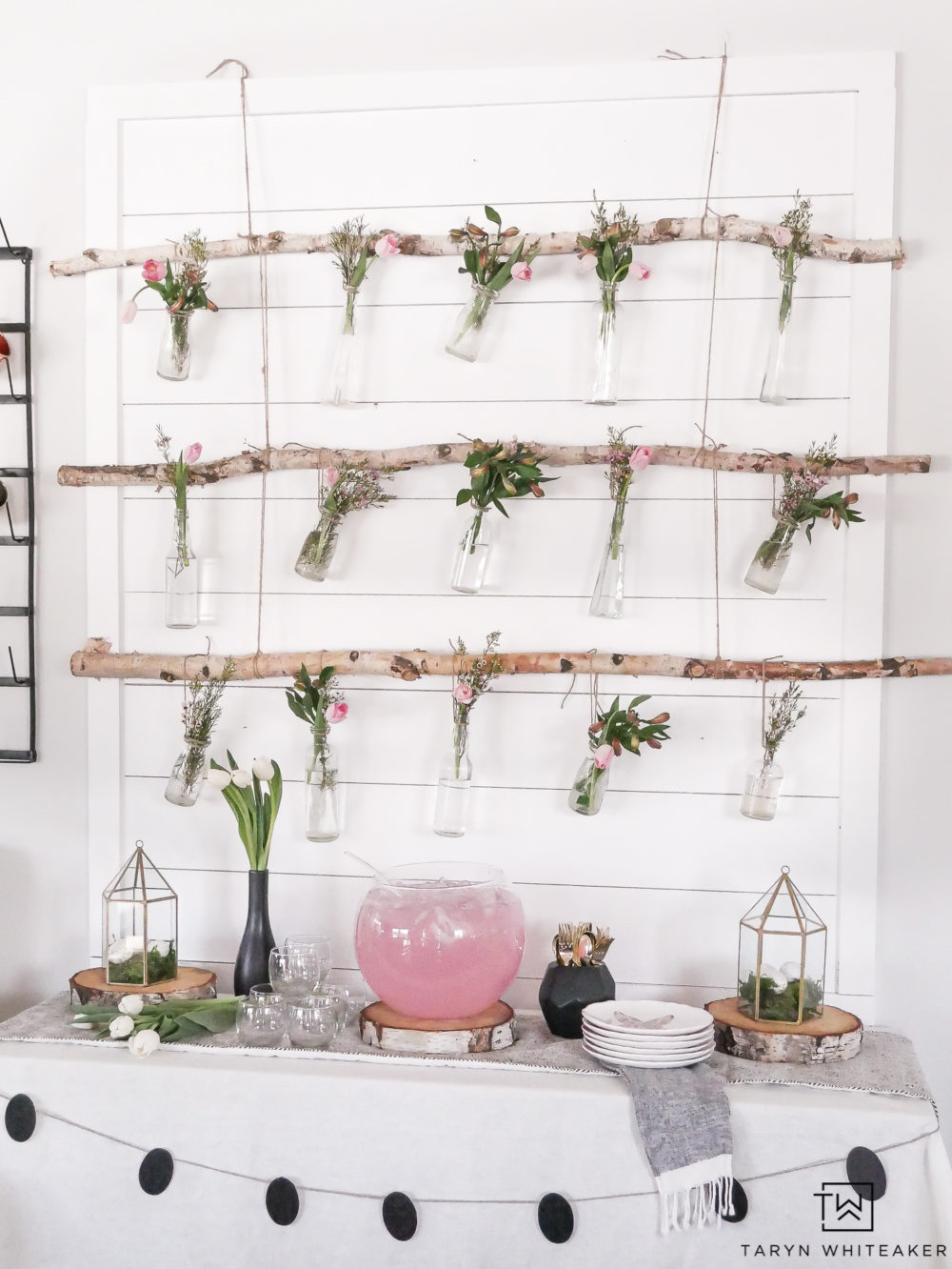 Create this Rustic Hanging Flower Display using birch branches and an eclectic mixture of glass vases! The pink flowers with greenery make it a sweet whimsical flower backdrop for a spring party.