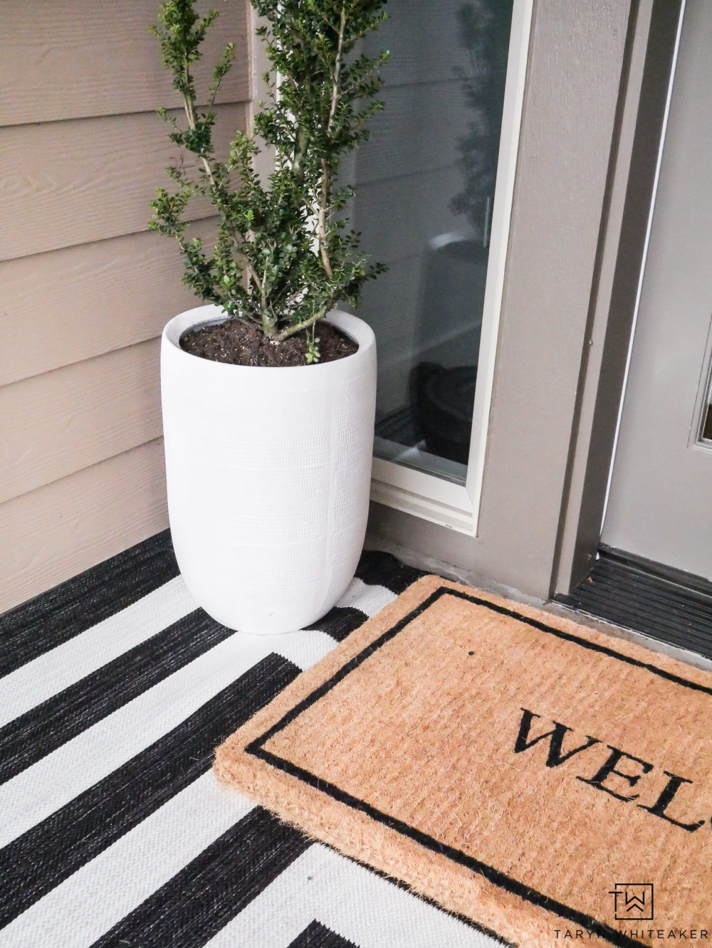 Click to get this Modern Spring Porch Decor look in your own home! The large white planters and layered rugs are simple yet impactful. 