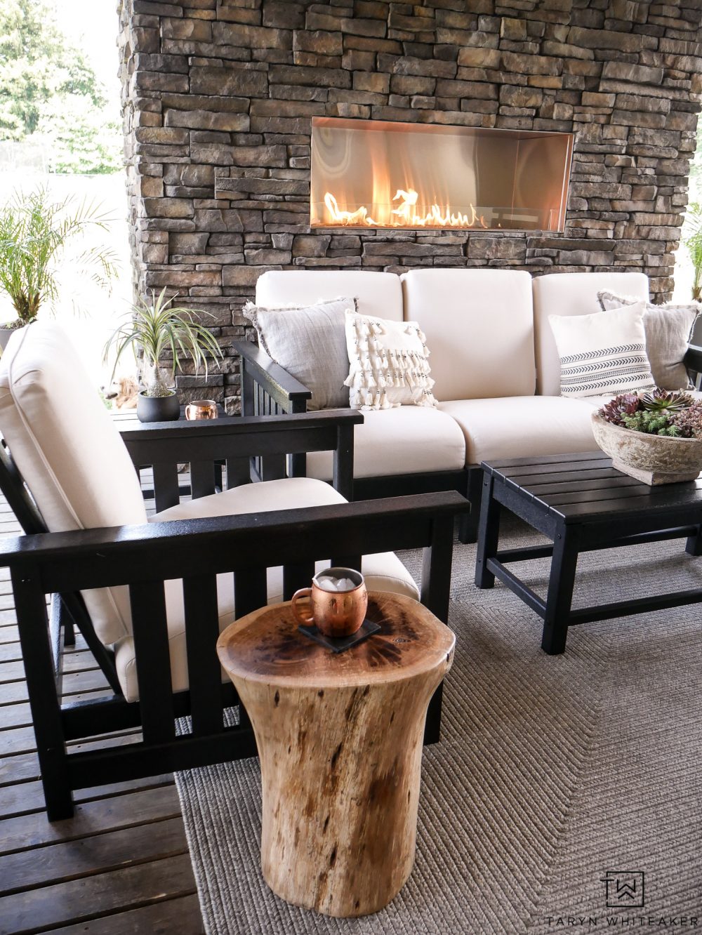 I love this gorgeous outdoor stone fireplace with all the modern furniture pieces. That wood stump side table brings such a great look to the space. 