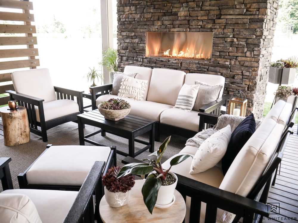 Such a beautiful outdoor living space complete with a stone fireplace and outdoor seating. This black and white furniture set looks so high-end and comfortable!