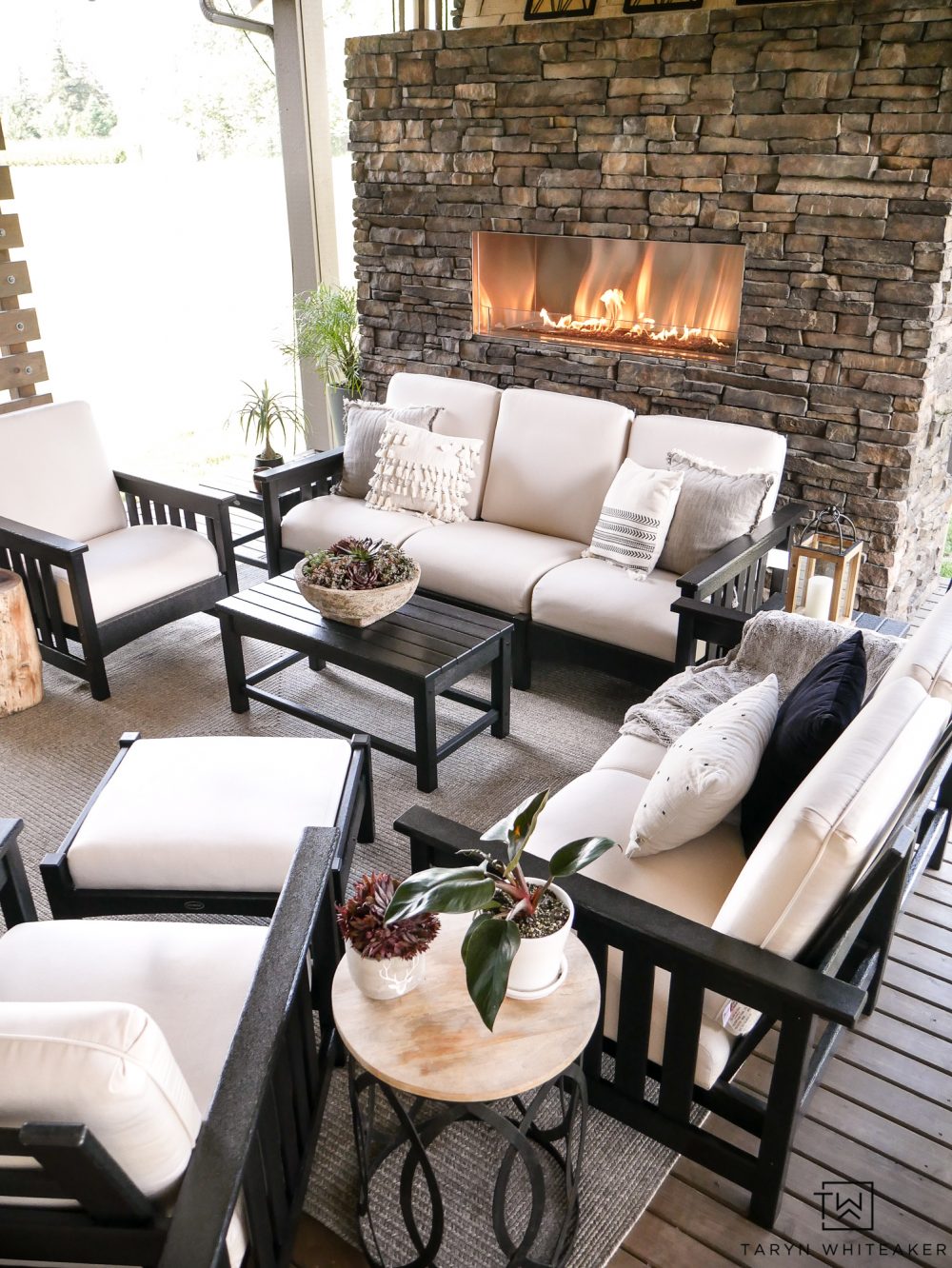 Luxurious outdoor living space with outdoor stone fireplace and beautiful black and white patio furniture. 