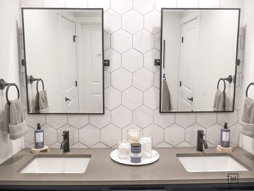 Come see what this bathroom looked like before! This double sink vanity was just a basic builder grade and now it has it's own custom modern look with marble looking hexagon tile, black pivot mirrors and charcoal blue cabinets! 