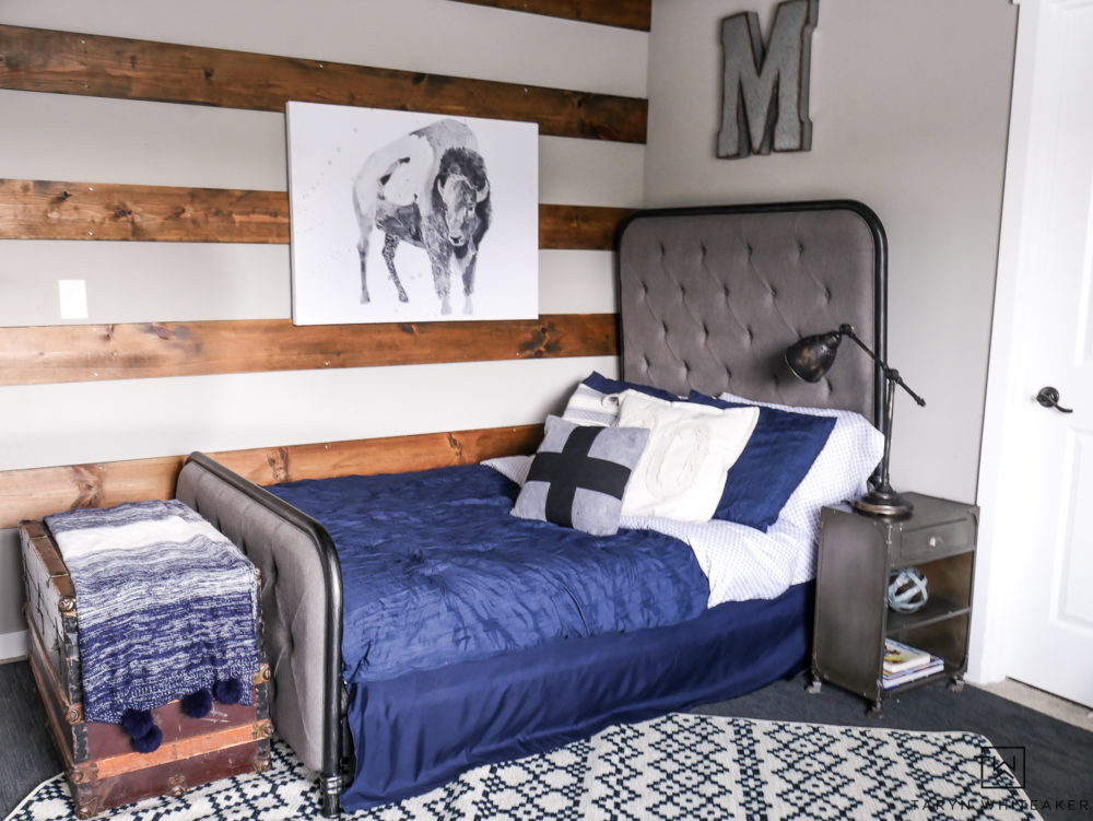 Modern farmhouse boy room design complete with high back headboard, navy blue bedding and patterned rug. 