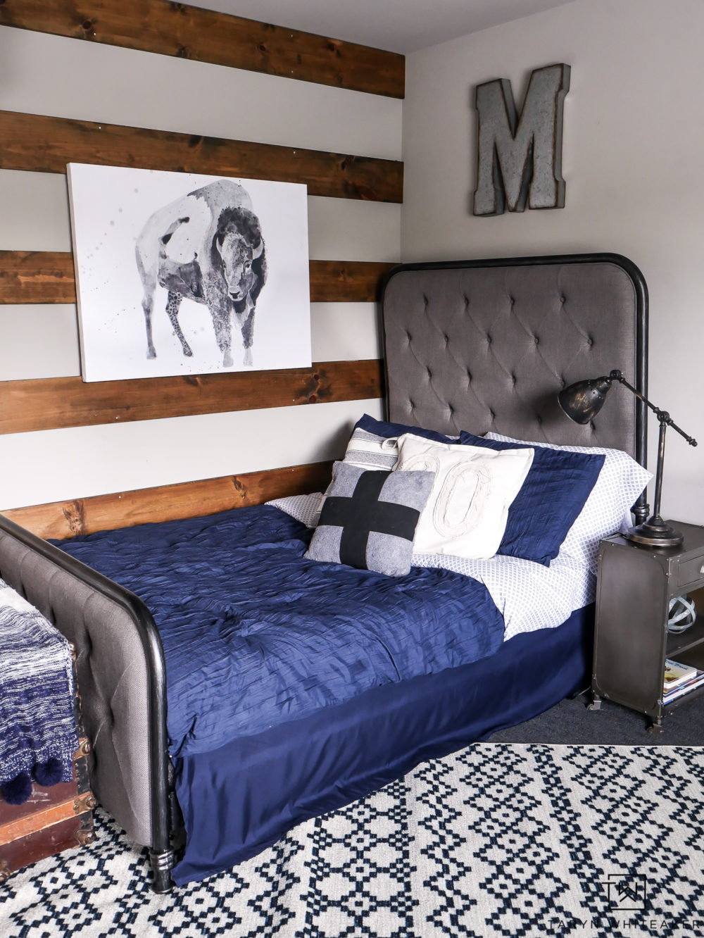 Love this rustic look for a boy room! The navy blue bedding and patterned rug mixed with wood tones and metals. 