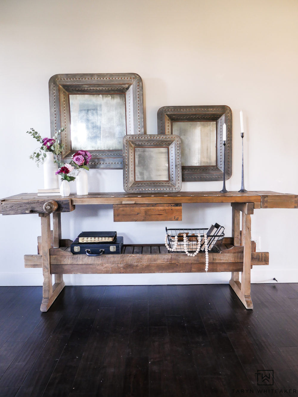 Give a welcoming look to your entry way with.a wood console table decorated with large scale items and soft fresh flowers. Mixing industrial and famine touches is a wonderful contrast.