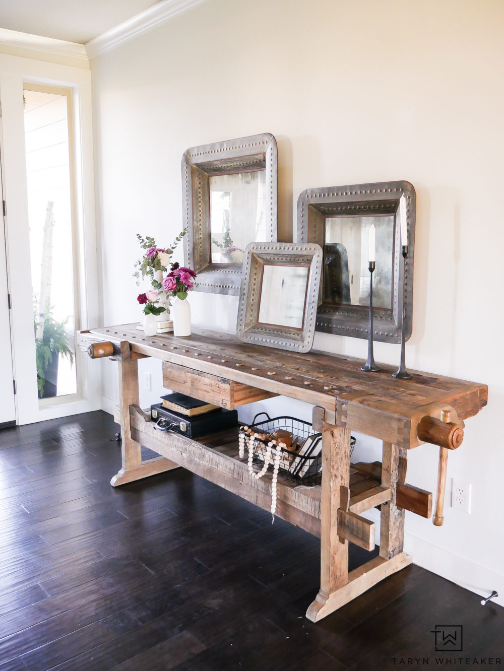 Give a welcoming look to your entry way with.a wood console table decorated with large scale items and soft fresh flowers. Mixing industrial and famine touches is a wonderful contrast.