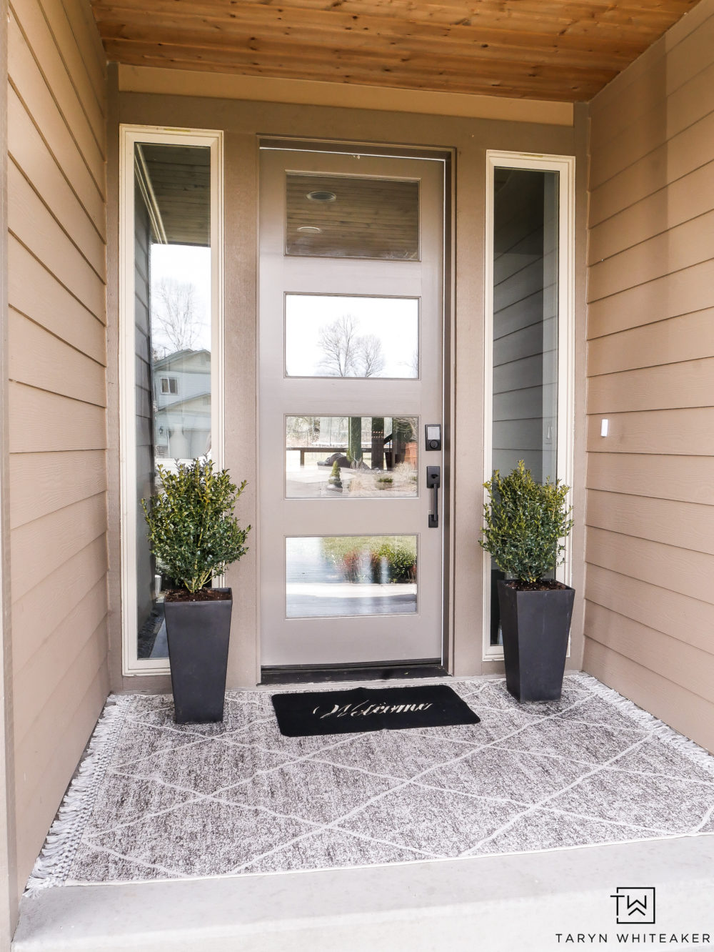 Classic spring porch decor with layered rugs and boxwood planters