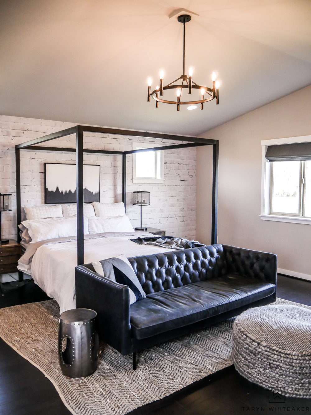 Modern industrial black and white master bedroom design with black hardwoods, canopy bed and black Chesterfield. 