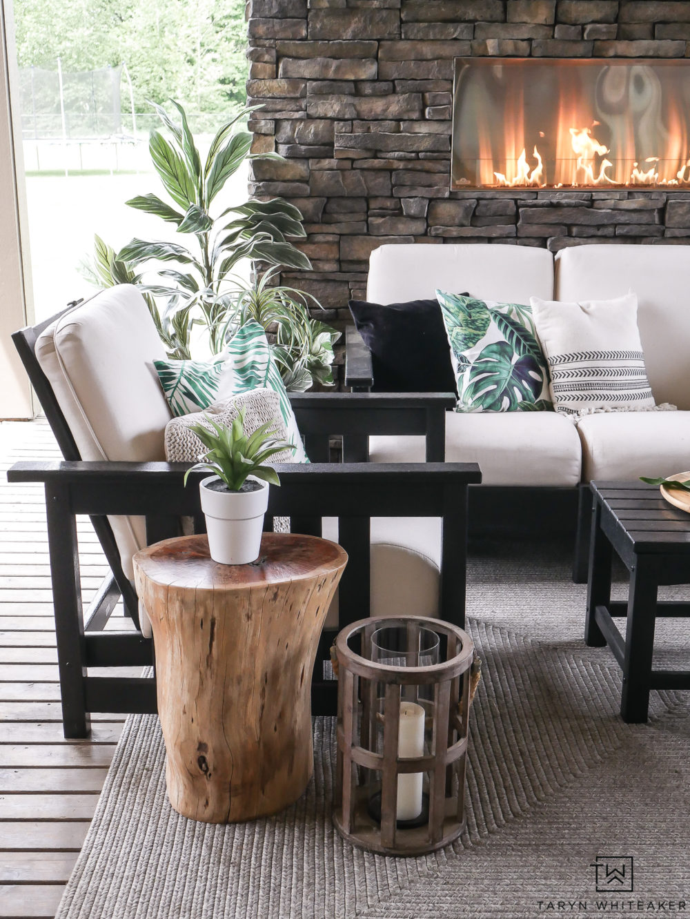 Black and White Outdoor living space with pops of tropical palms. Great take on Modern Coastal Decor. Adorable stump table and lanterns. 