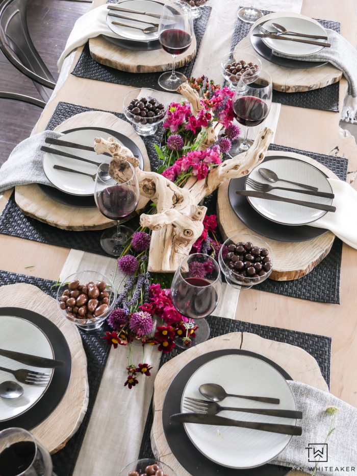 Beautiful black and white rustic modern tablescape with pops of earth tones! Love  how the purple and pink flowers look on the centerpiece. 