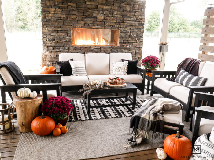 Learn how to turn your outdoor living space into a cozy fall escape using pumpkins, mums and plaid blankets. This outdoor fall decor is simple and inviting. 
