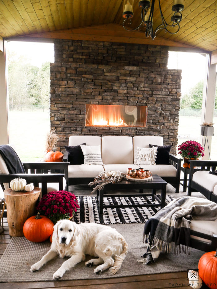 Learn how to turn your outdoor living space into a cozy fall escape using pumpkins, mums and plaid blankets. This outdoor fall decor is simple and inviting. 