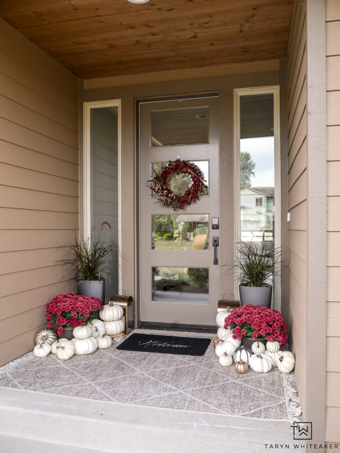 This modern fall porch decor is classic and elegant. The red mums and white pumpkins paired with the black planters gives the proch a bold look for fall.