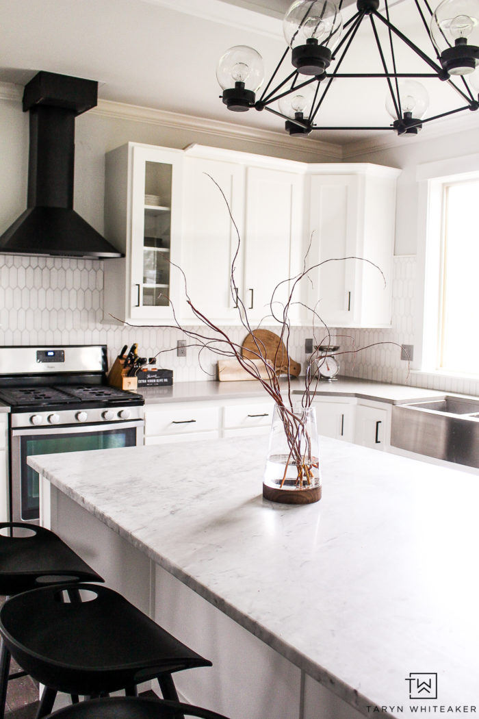 Black and white modern kitchen with black range hood and natural accents.  