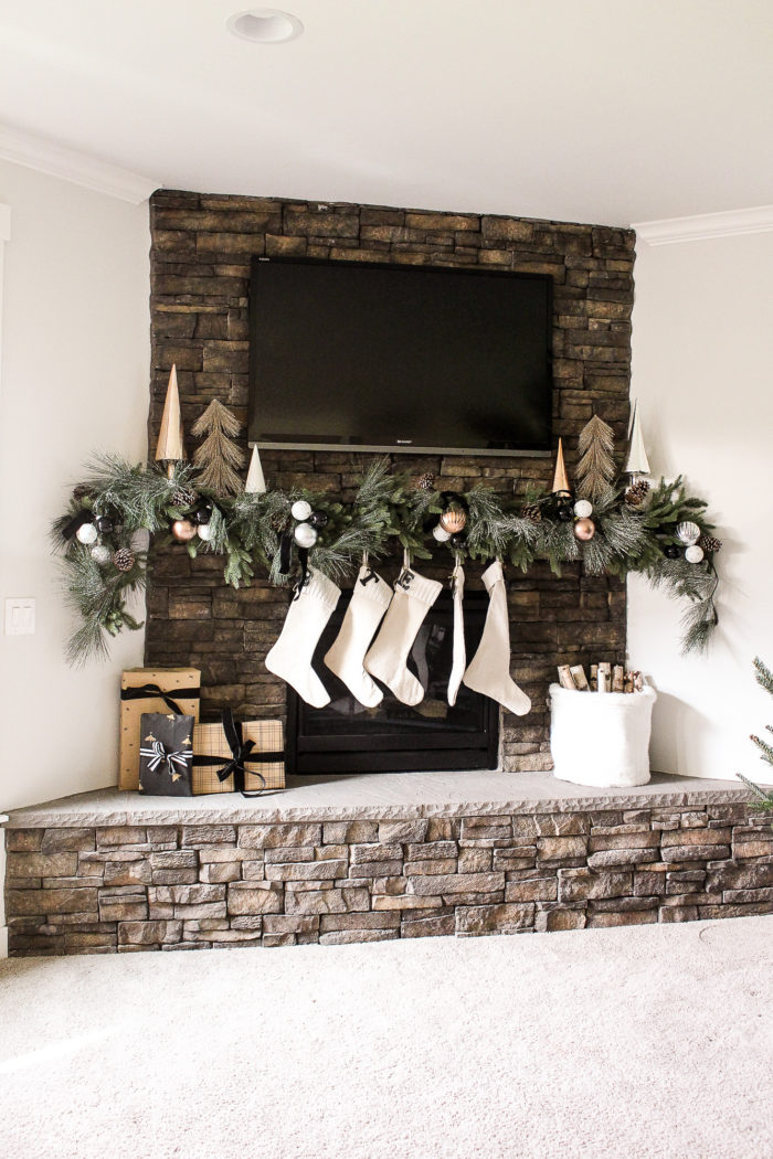 Simple Christmas Mantel using lush greenery over mantel and metallic ornaments tucked throughout. 