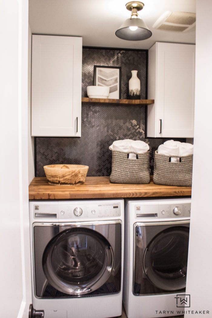 Tour this Rustic Modern Laundry Room that you can easily DIY yourself! From pre-made cabinets, butcher block countertops and peel and stick tile backsplash!