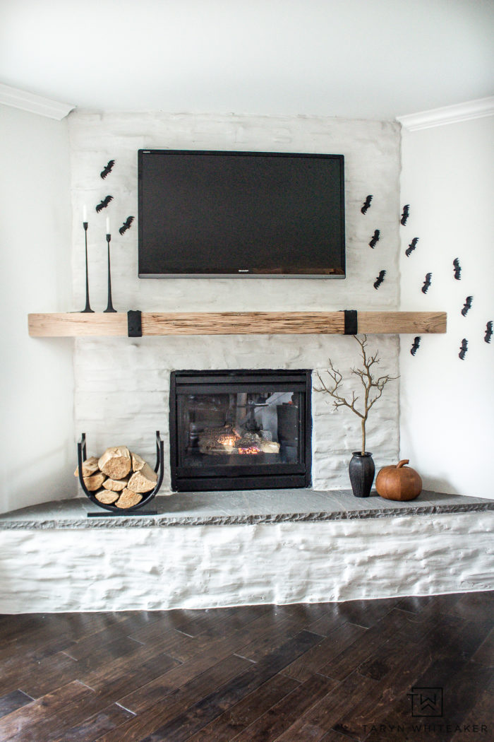 Create your own Minimalistic Halloween Mantel Decor with these simple ideas of a cascading bat display, branches and a few pumpkins! 
