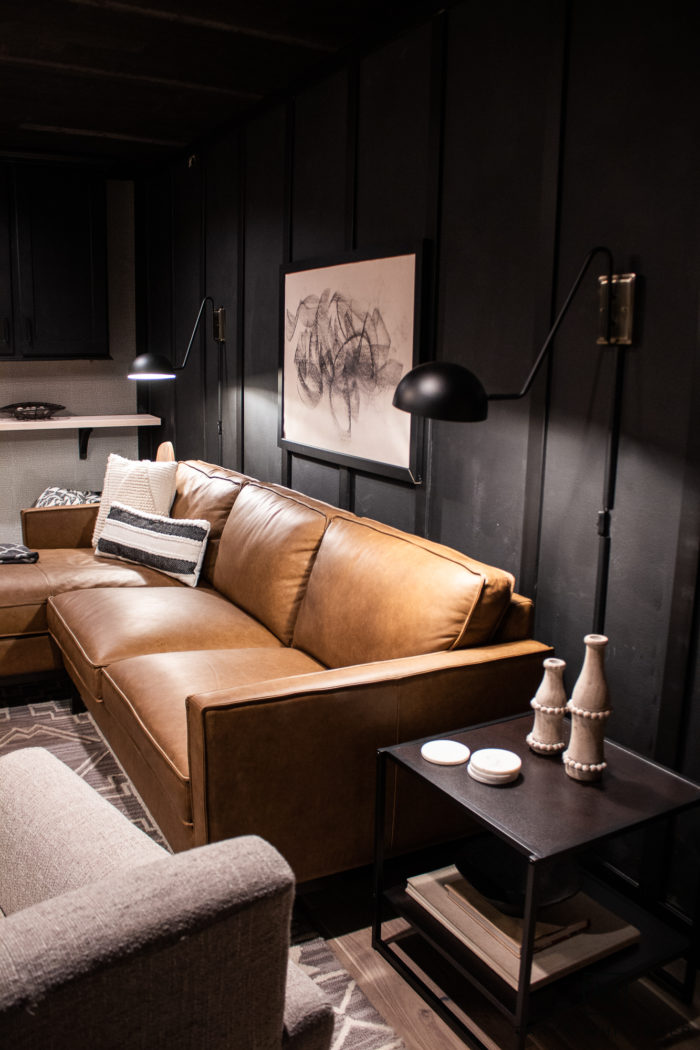 Modern mid-century modern bonus room with leather sofa and dark accents. 