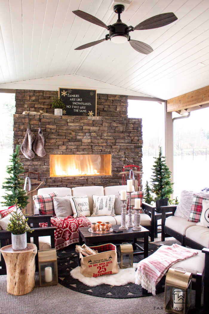 Tour this Christmas outdoor fireplace all decorated for the holidays with a cabin chic vibe! It's all about trees, pillows and staying cozy!