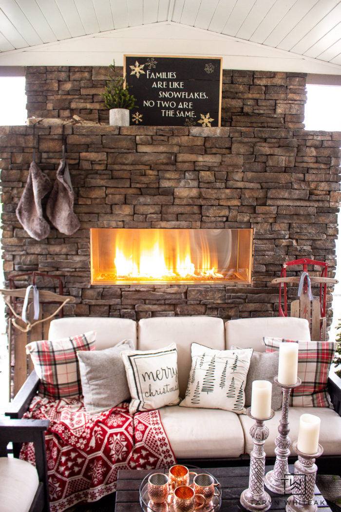 Tour this Christmas outdoor fireplace all decorated for the holidays with a cabin chic vibe! It's all about trees, pillows and staying cozy!