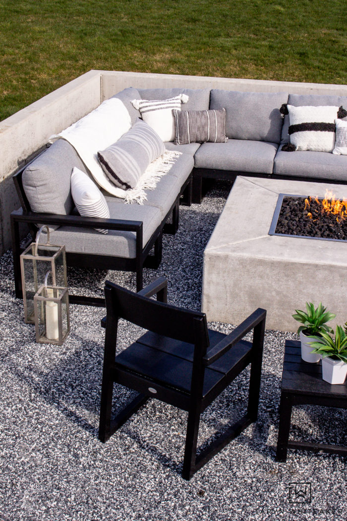 Neutral modern outdoor furniture with grey sectional and lots of black and white outdoor pillows. 