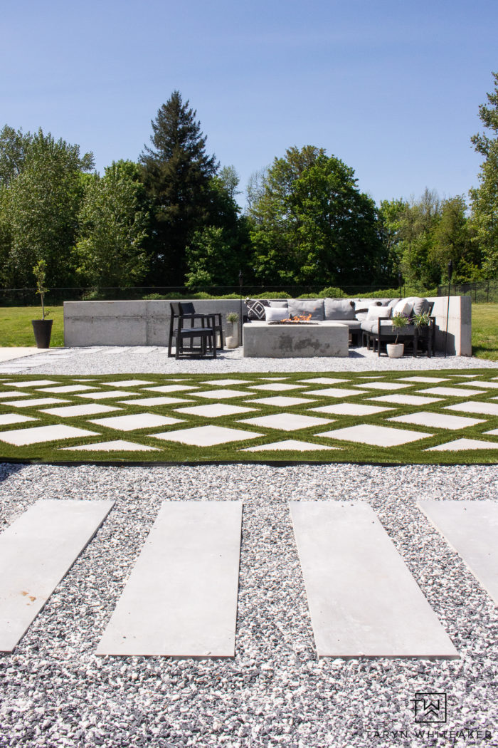 Backyard landscape design with concrete fire pit and modern outdoor space complete with grid style turf. 