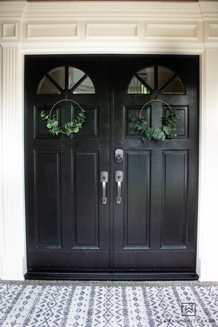 black front door with minimalistic eucalyptus wreaths