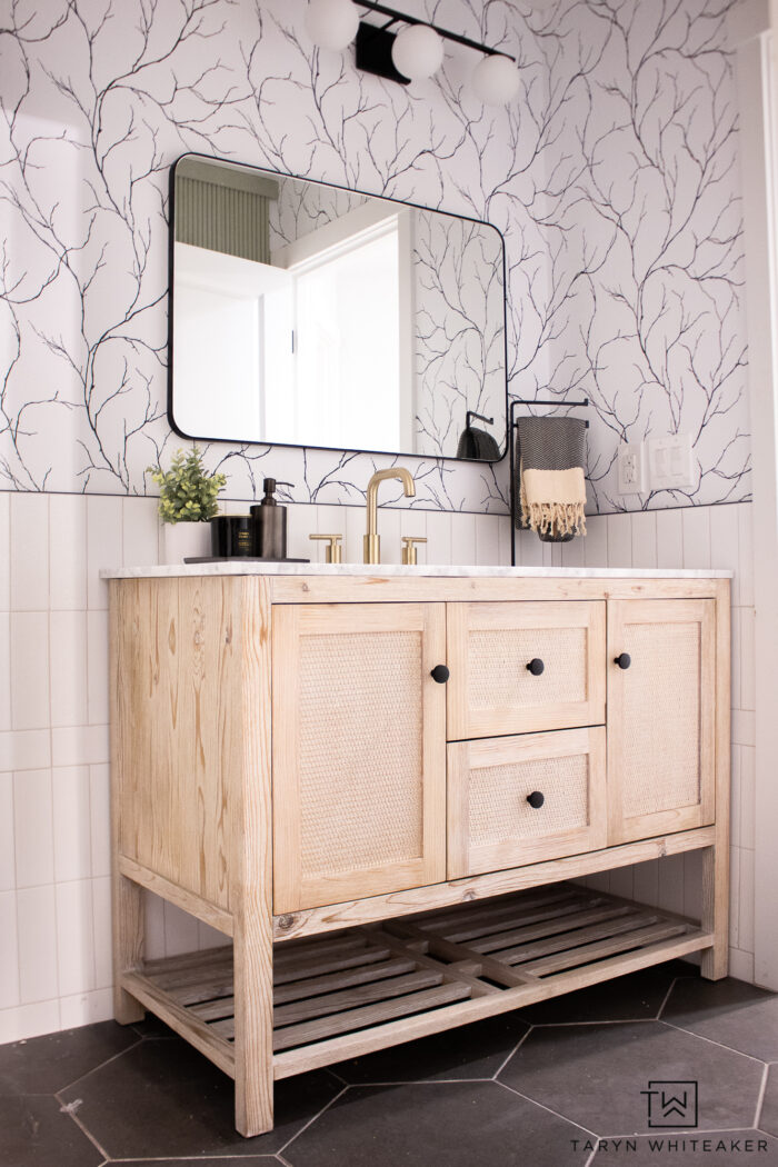 First peek of the Black and White Bathroom Vanity with rattan vanity, hexagon floor and half wall subway tile. 