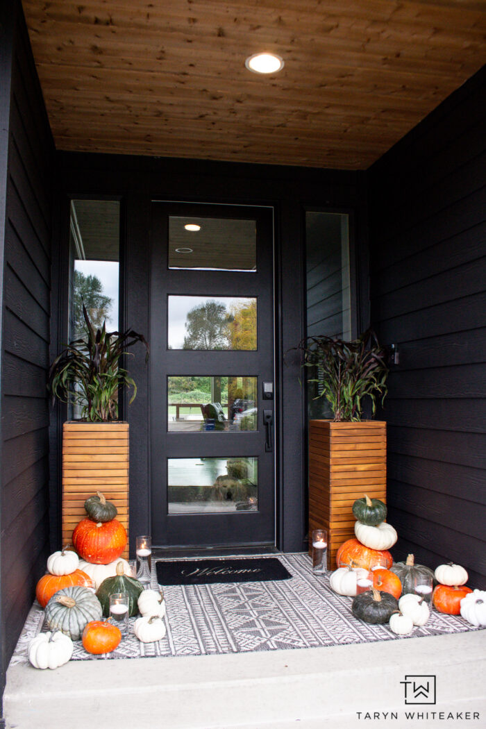 Modern fall porch display with dark exterior and heirloom pumpkins