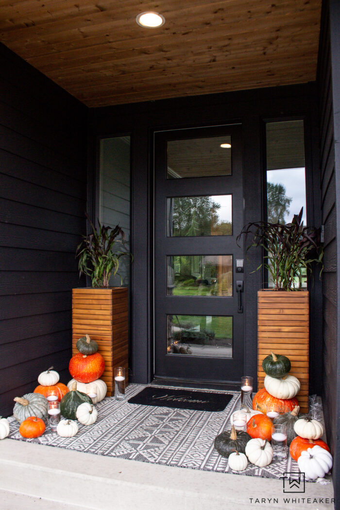 Modern fall porch display with dark exterior and heirloom pumpkins