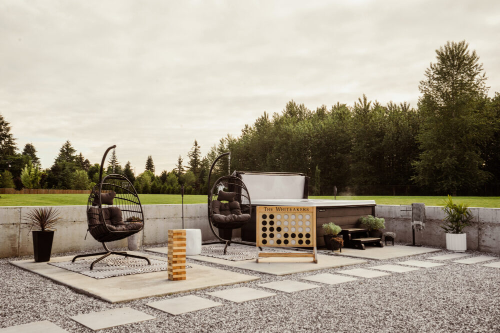 Modern outdoor living space with hanging egg chairs and hot tub with yard games for the whole family to enjoy. 