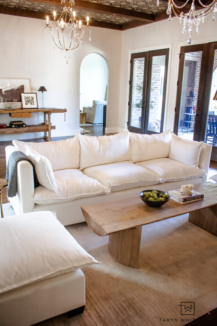 White modern sofa and accent chairs with natural wood coffee table and decor. 