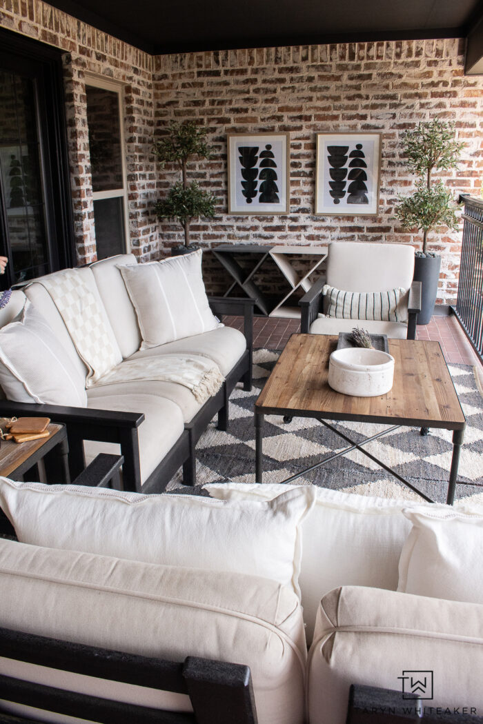 Modern and moody French Country patio decor with checkered rugs, POLYWOOD furniture and neutral tones, lots of greenery and modern touches. 