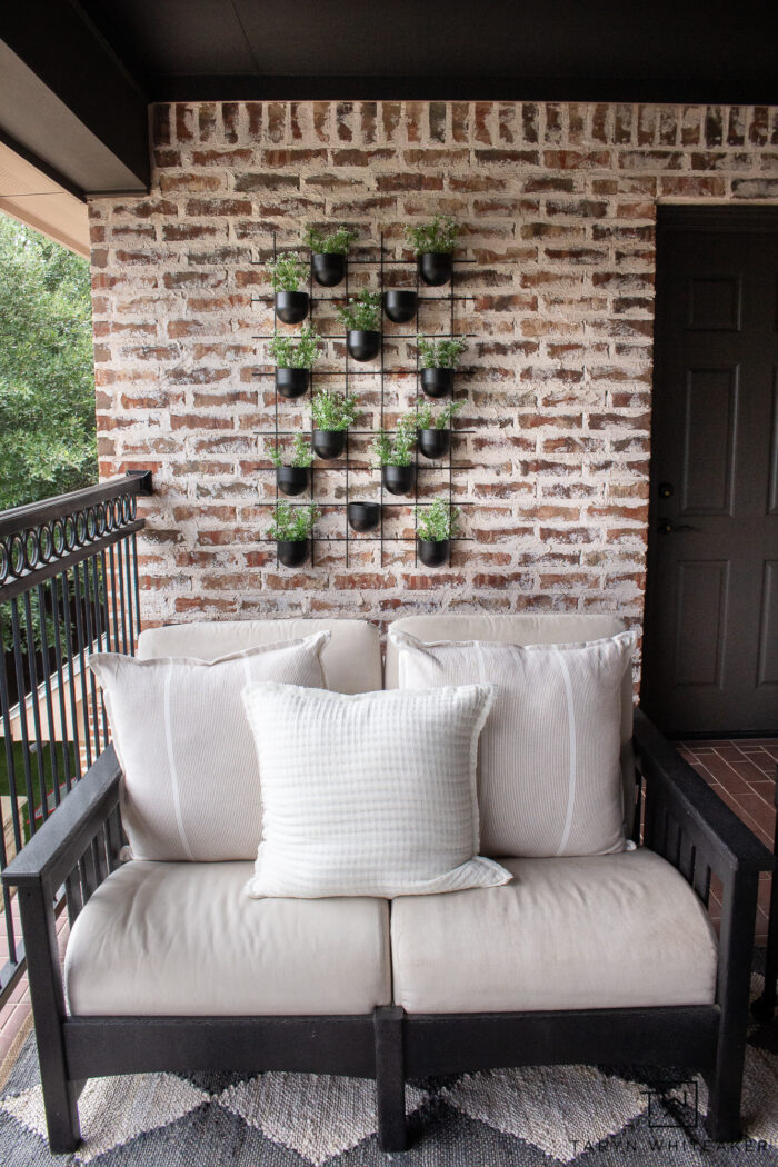 Patio with dark ceiling and greenery against brick wall. 