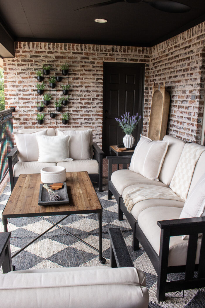 Modern French Country outdoor decor. Tour this space and get the sources for this look. Moody ceiling and dark trim against the brick walls create a modern contrast to a traditional exterior. 