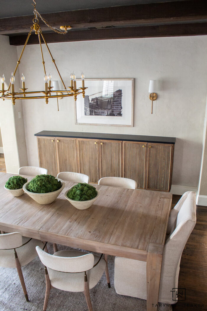 Modern organic dining room decor with white washed rustic dining table, upholstered captains chairs, fluted buffet