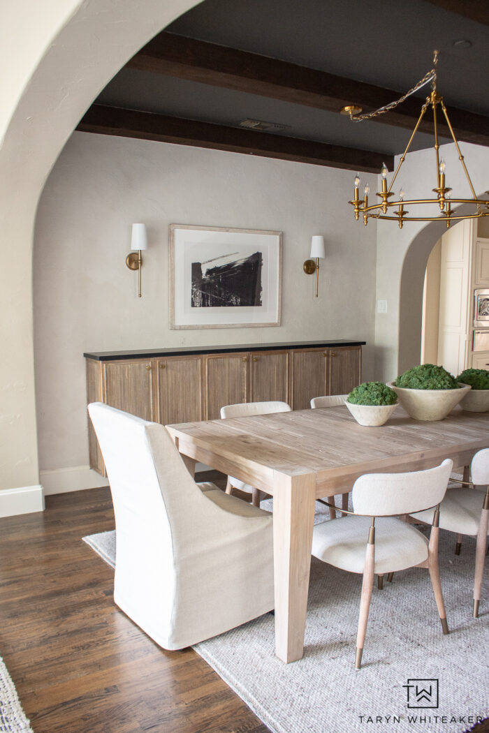 Modern organic dining room decor with white washed rustic dining table, upholstered captains chairs, fluted buffet