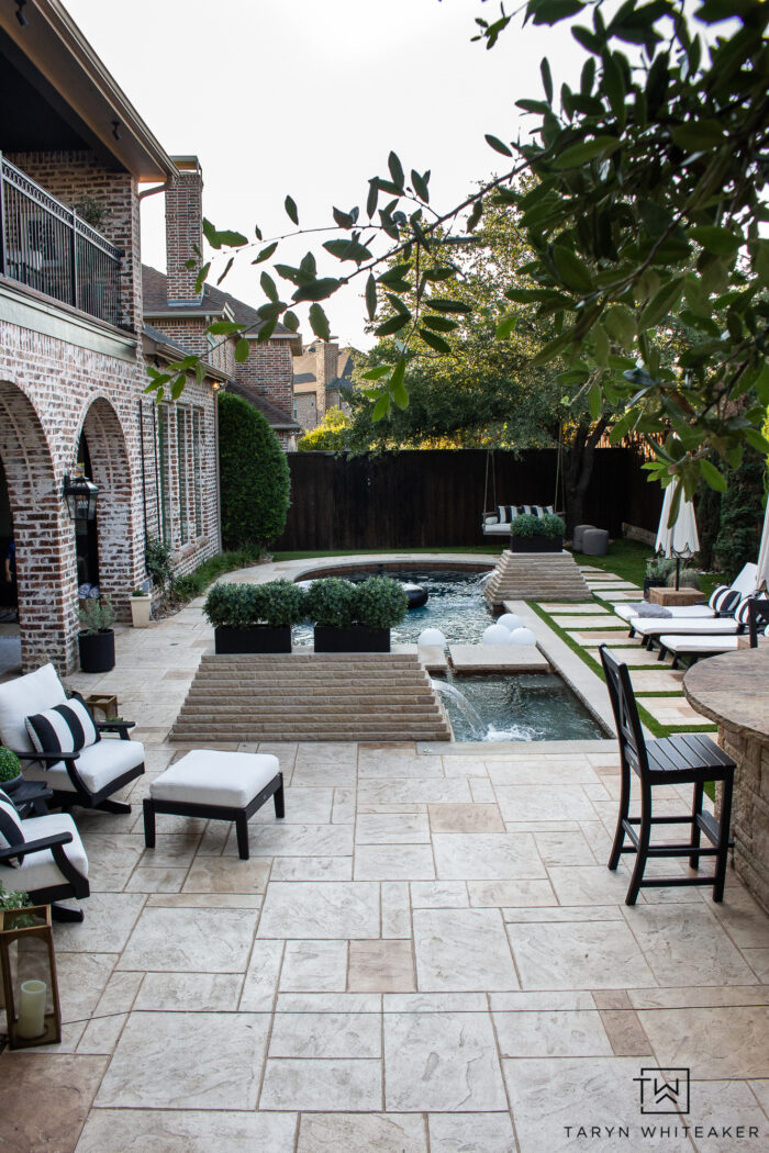 Tour this Modern English Country Backyard featuring classic black and white outdoor furniture and decor with greenery and brick exterior. 