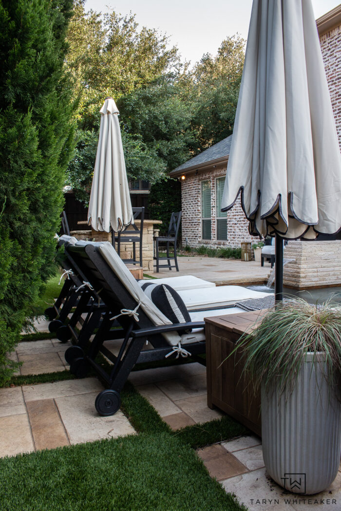 Tour this Modern English Country Backyard featuring classic black and white outdoor furniture and decor with greenery and brick exterior. 