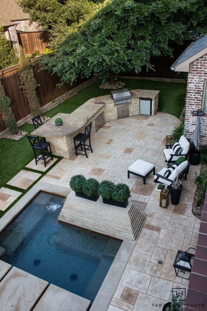 Tour this Modern English Country Backyard featuring classic black and white outdoor furniture and decor with greenery and brick exterior. 