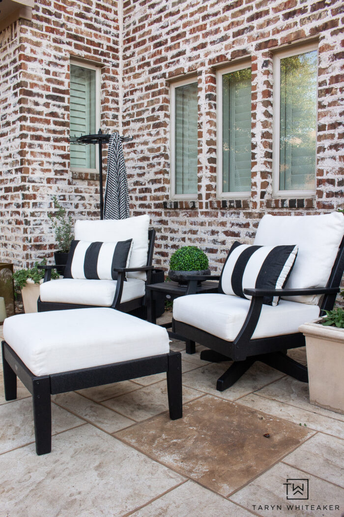 Tour this Modern English Country Backyard featuring classic black and white outdoor furniture and decor with greenery and brick exterior. 